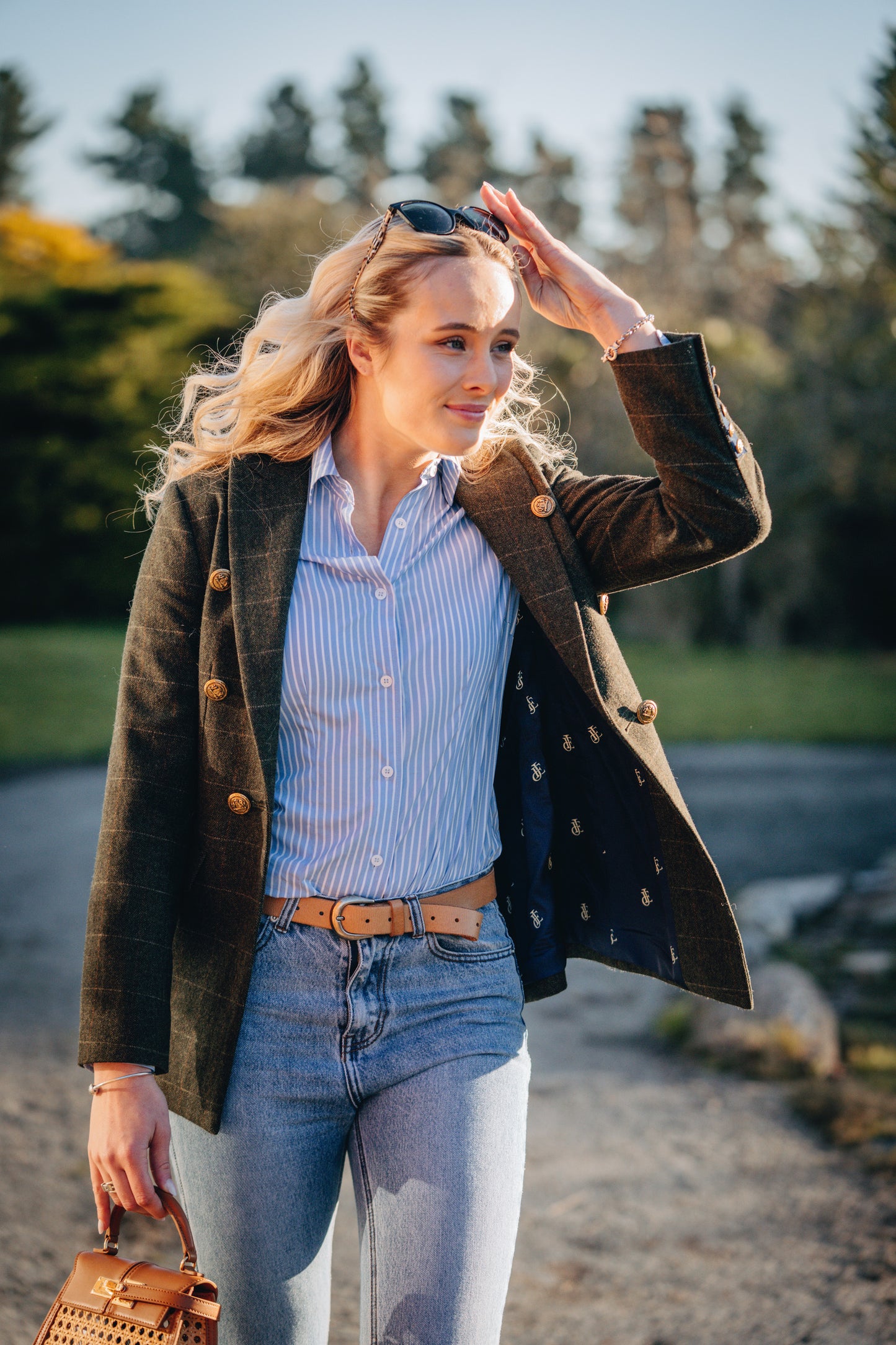 Woman wearing a green coat, blue striped shirt, and jeans outdoors.