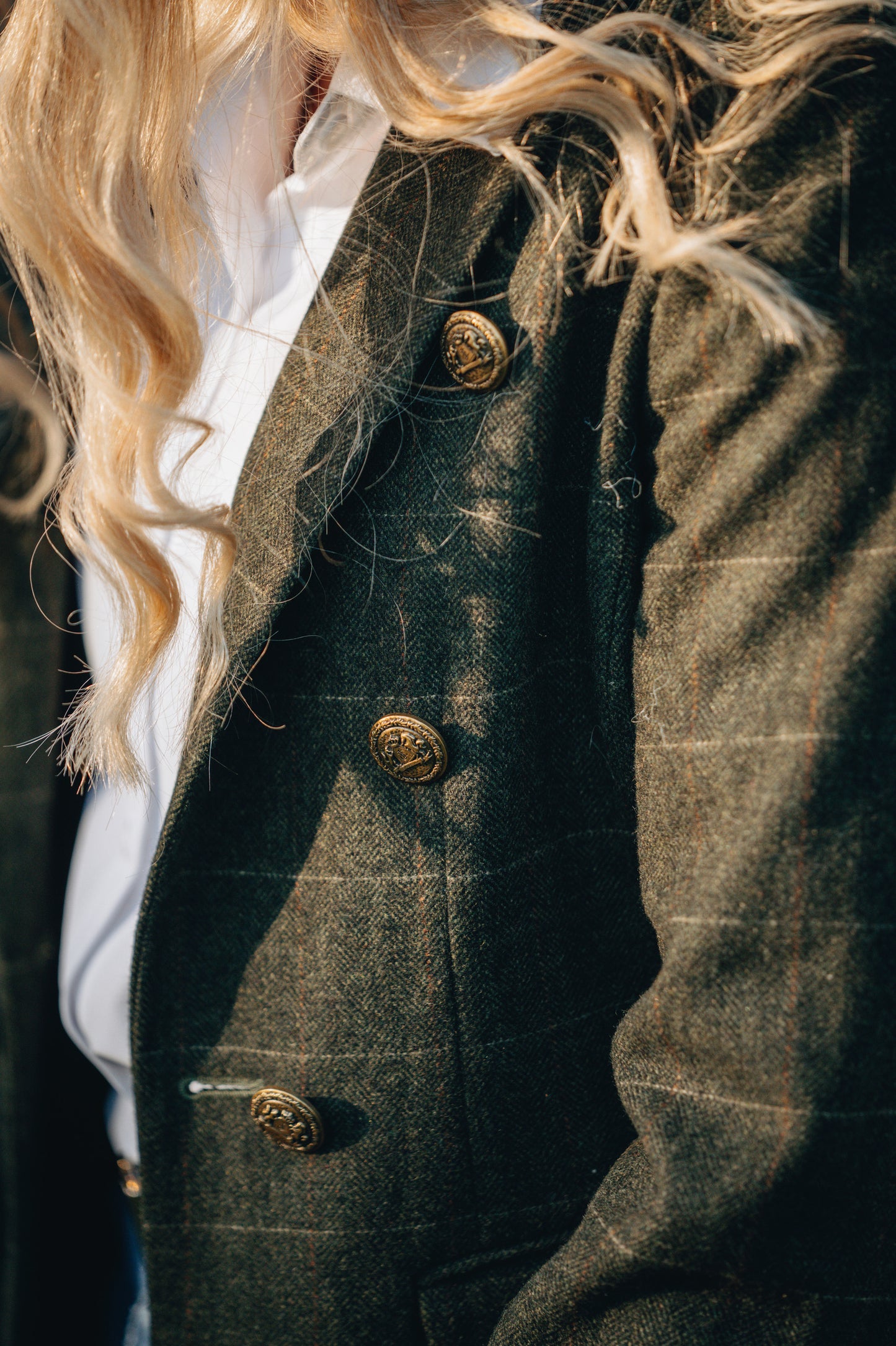 Close-up of a person wearing a dark green textured coat with gold buttons.
