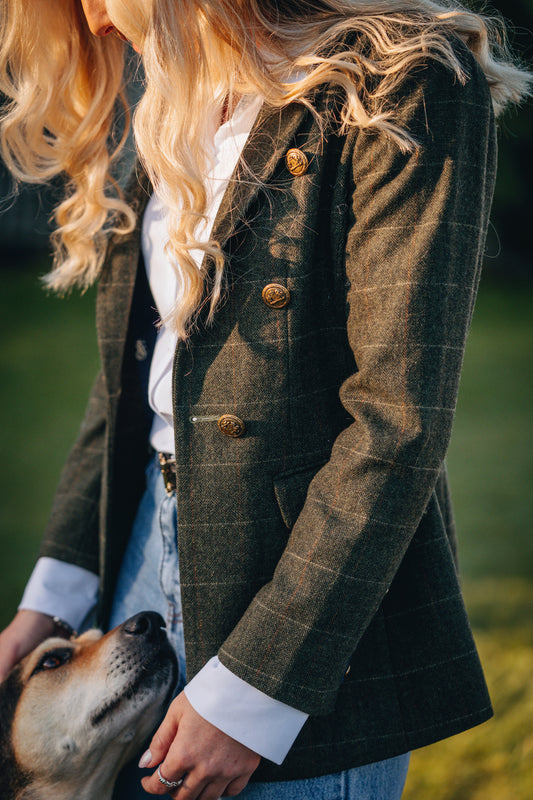 Person wearing a green checkered coat with a dog in a natural setting