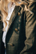 Close-up of a person wearing a dark green textured coat with gold buttons.